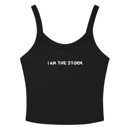 "I am the storm" printed on a solid black blend women's micro-rib tanktop laying on a flat surface amongst sunglasses and shorts