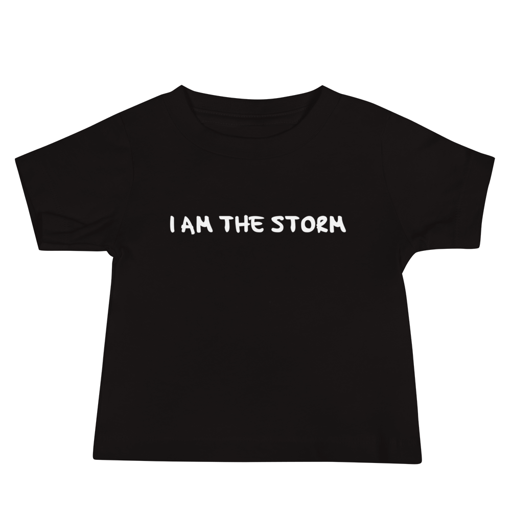 "I am the storm" printed on a black baby jersey short sleeve tee laying on a flat surface