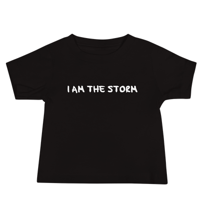 "I am the storm" printed on a black baby jersey short sleeve tee laying on a flat surface