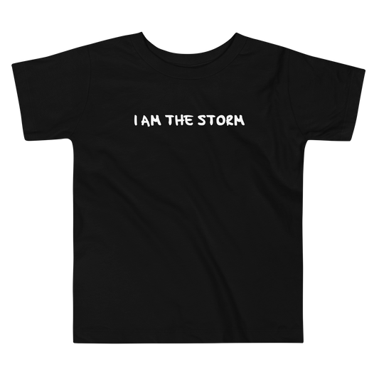 "I am the storm" printed on a black toddler short sleeve tee laying on a flat surface