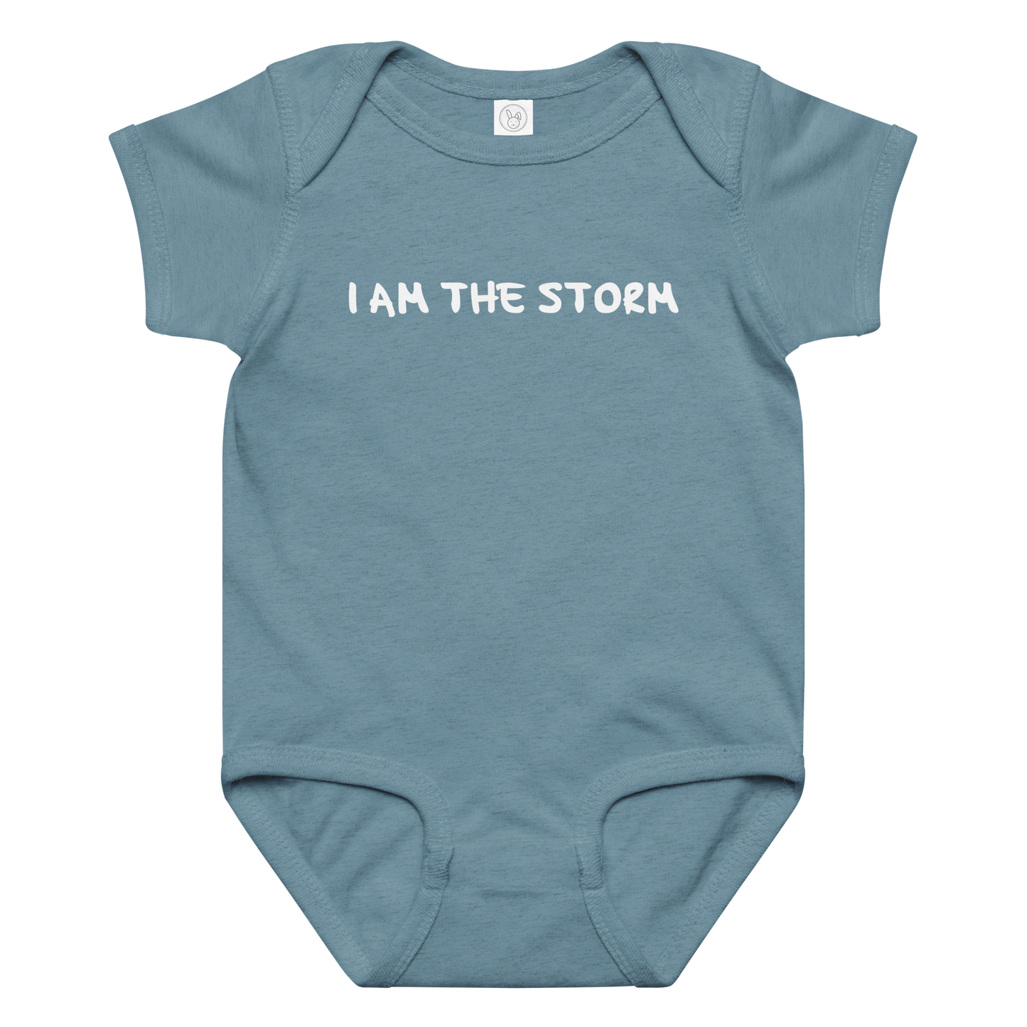 "I am the storm" printed on a vintage indigo baby jersey bodysuit laying on a flat surface amongst other clothes