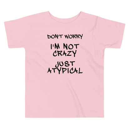 "Don't Worry I'm Not Crazy Just Atypical" printed on a pink toddler short sleeve tee laying on a flat surface