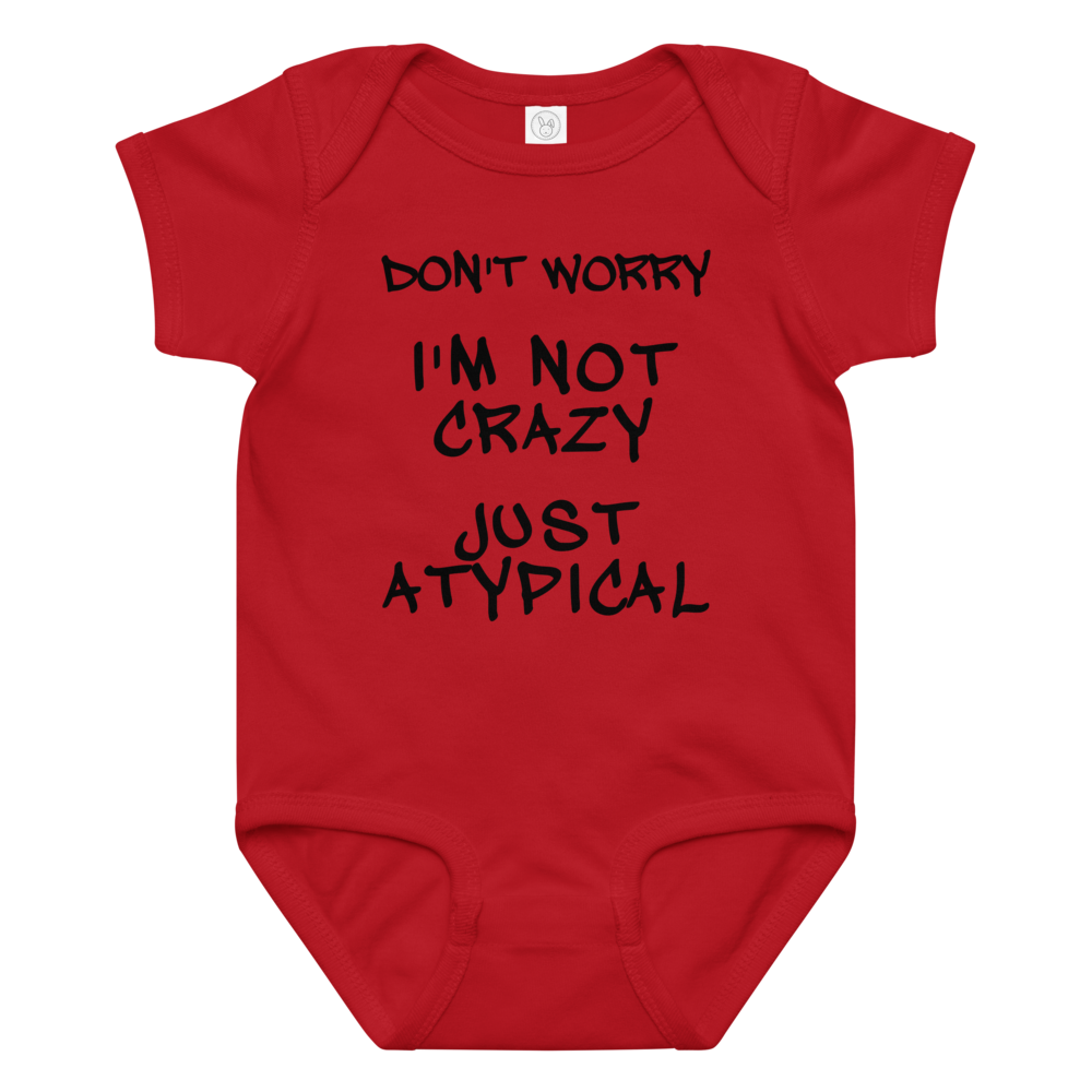 "Don't Worry I'm Not Crazy Just Atypical" printed on a red baby jersey bodysuit laying on a flat surface amongst other clothes