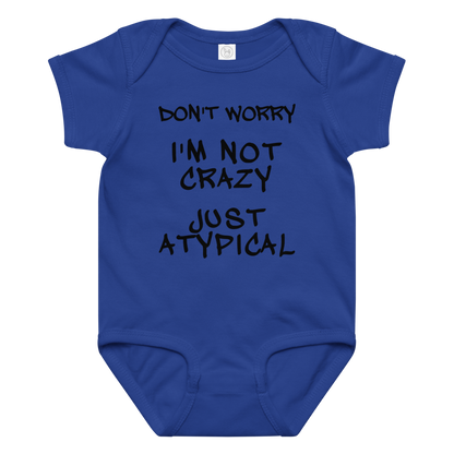 "Don't Worry I'm Not Crazy Just Atypical" printed on a royal baby jersey bodysuit laying on a flat surface amongst other clothes