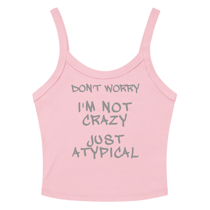 "Don't Worry I'm Not Crazy Just Atypical" printed on a solid pink blend women's micro-rib tanktop laying on a flat surface amongst sunglasses and shorts