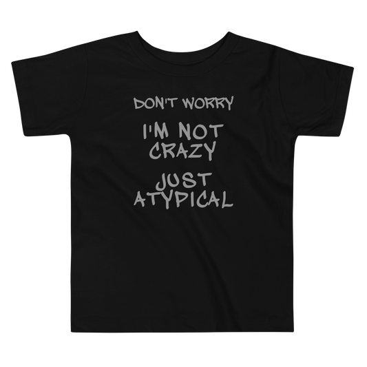 "Don't Worry I'm Not Crazy Just Atypical" printed on a black toddler short sleeve tee laying on a flat surface