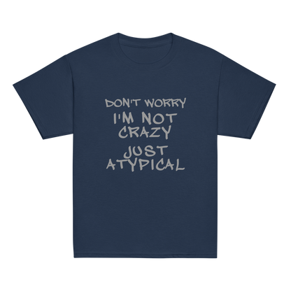 "Don't Worry I'm Not Crazy Just Atypical" printed on a navy youth classic tee laying on a flat surface