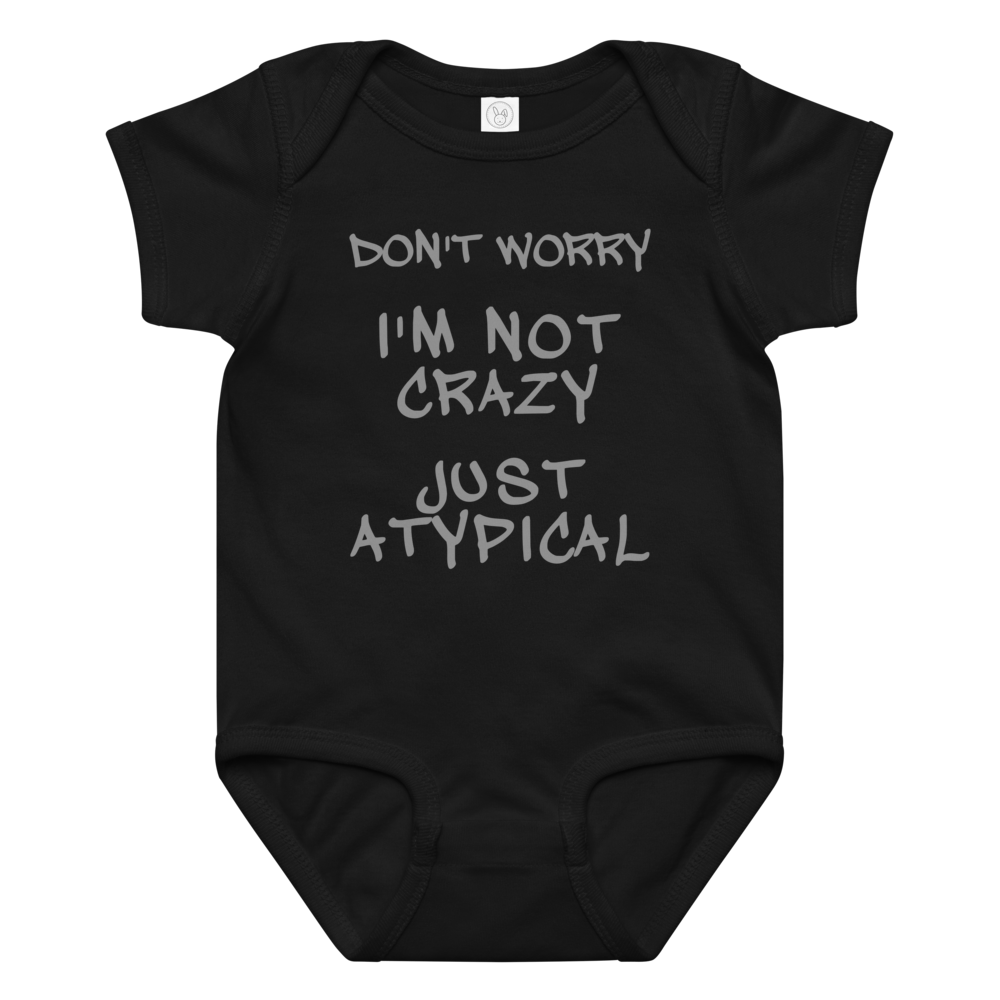 "Don't Worry I'm Not Crazy Just Atypical" printed on a black baby jersey bodysuit laying on a flat surface amongst other clothes