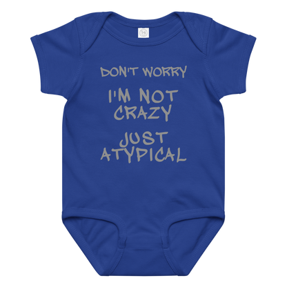 "Don't Worry I'm Not Crazy Just Atypical" printed on a royal baby jersey bodysuit laying on a flat surface amongst other clothes
