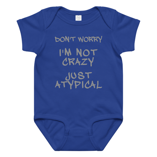 "Don't Worry I'm Not Crazy Just Atypical" printed on a royal baby jersey bodysuit laying on a flat surface amongst other clothes