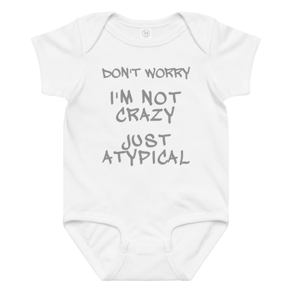 "Don't Worry I'm Not Crazy Just Atypical" printed on a white baby jersey bodysuit laying on a flat surface amongst other clothes