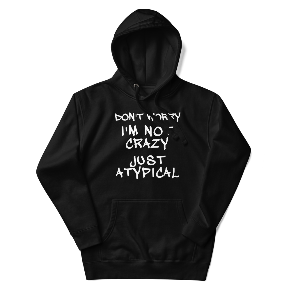 "Don't Worry I'm Not Crazy Just Atypical" printed on a black unisex hoodie laying on a flat surface with the hood up