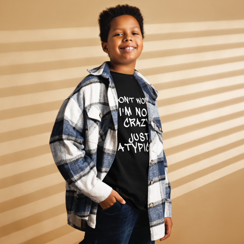 "Don't Worry I'm Not Crazy Just Atypical" printed on a black youth classic tee worn by a male also wearing a jacket