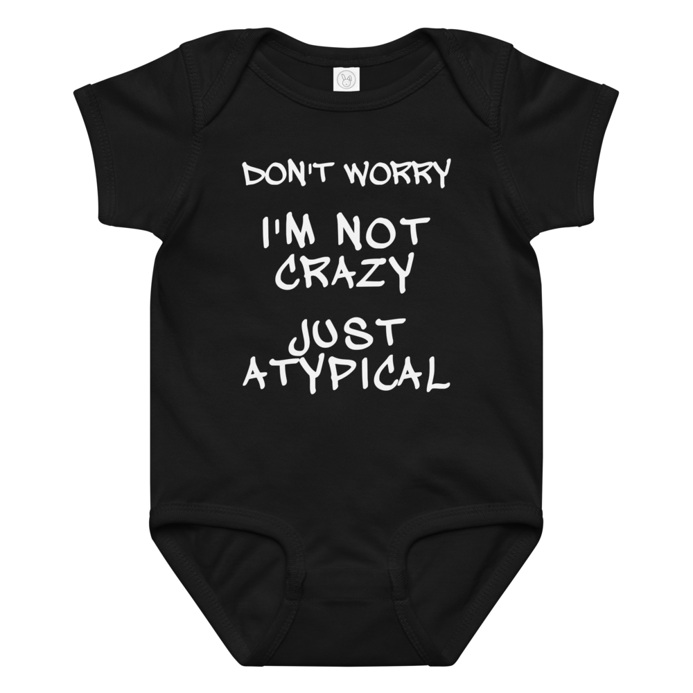 "Don't Worry I'm Not Crazy Just Atypical" printed on a black baby jersey bodysuit laying on a flat surface amongst other clothes