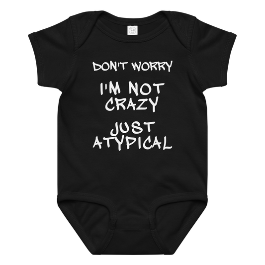 "Don't Worry I'm Not Crazy Just Atypical" printed on a black baby jersey bodysuit laying on a flat surface amongst other clothes