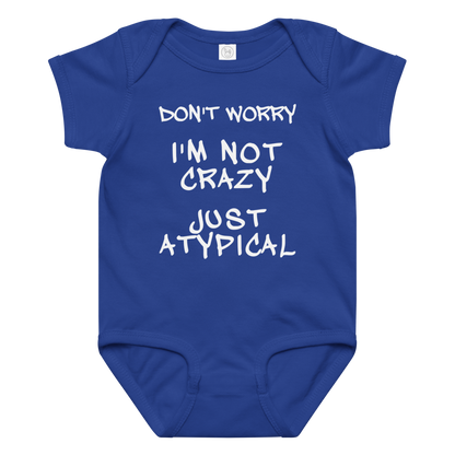 "Don't Worry I'm Not Crazy Just Atypical" printed on a royal baby jersey bodysuit laying on a flat surface amongst other clothes