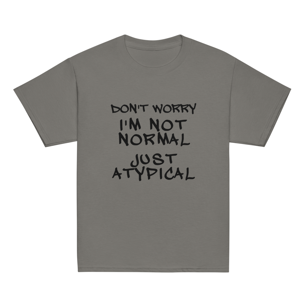 "Don't Worry I'm Not Normal Just Atypical" printed on a charcoal youth classic tee laying on a flat surface