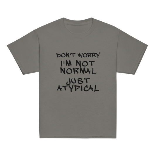 "Don't Worry I'm Not Normal Just Atypical" printed on a charcoal youth classic tee laying on a flat surface