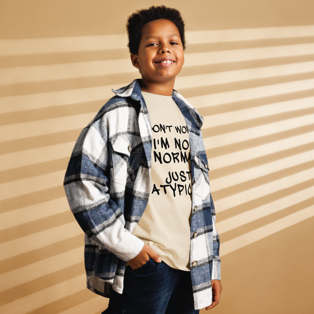 "Don't Worry I'm Not Normal Just Atypical" printed on a natural youth classic tee worn by a male also wearing a jacket
