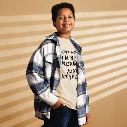 "Don't Worry I'm Not Normal Just Atypical" printed on a natural youth classic tee worn by a male also wearing a jacket
