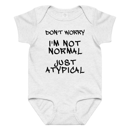 "Don't Worry I'm Not Normal Just Atypical" printed on a ash baby jersey bodysuit laying on a flat surface amongst other clothes