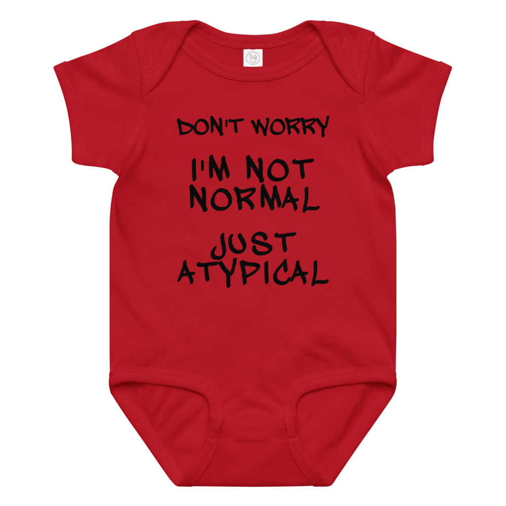 "Don't Worry I'm Not Normal Just Atypical" printed on a red baby jersey bodysuit laying on a flat surface amongst other clothes