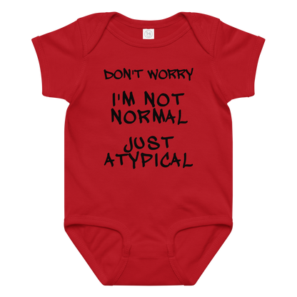 "Don't Worry I'm Not Normal Just Atypical" printed on a red baby jersey bodysuit laying on a flat surface amongst other clothes