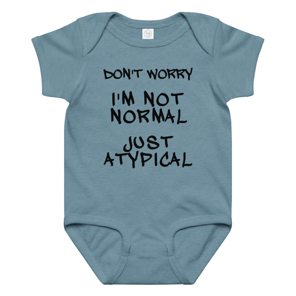"Don't Worry I'm Not Normal Just Atypical" printed on a vintage indigo baby jersey bodysuit laying on a flat surface amongst other clothes