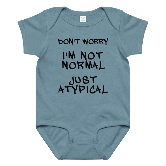 "Don't Worry I'm Not Normal Just Atypical" printed on a vintage indigo baby jersey bodysuit laying on a flat surface amongst other clothes