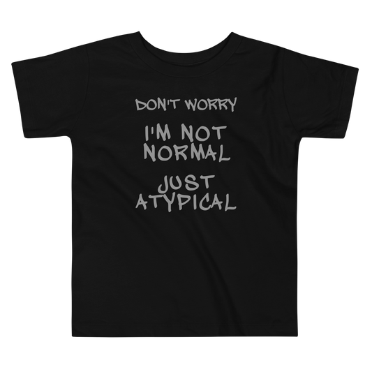 "Don't Worry I'm Not Normal Just Atypical" printed on a black toddler short sleeve tee laying on a flat surface