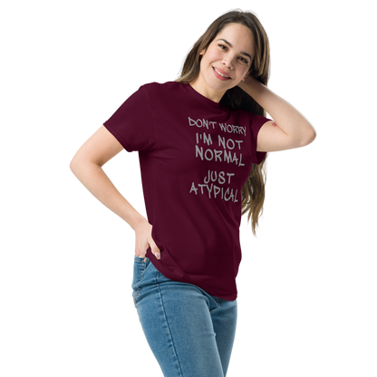 "Don't Worry I'm Not Normal Just Atypical" printed on a maroon unisex classic tee worn by a female