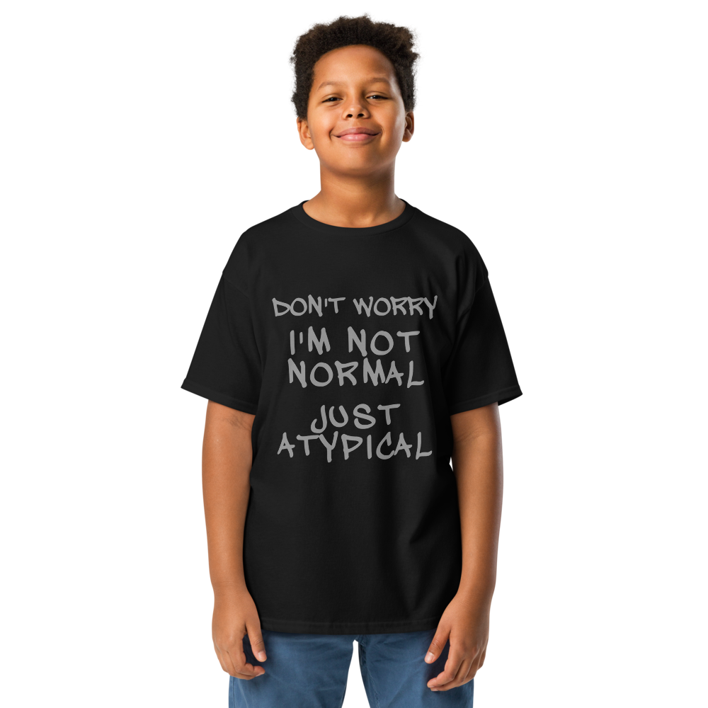 "Don't Worry I'm Not Normal Just Atypical" printed on a black youth classic tee worn by a male