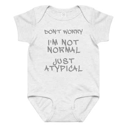 "Don't Worry I'm Not Normal Just Atypical" printed on a ash baby jersey bodysuit laying on a flat surface amongst other clothes