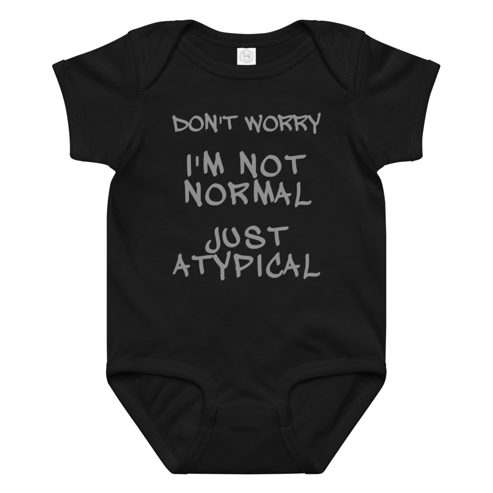 "Don't Worry I'm Not Normal Just Atypical" printed on a black baby jersey bodysuit laying on a flat surface amongst other clothes