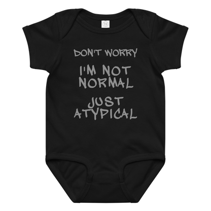 "Don't Worry I'm Not Normal Just Atypical" printed on a black baby jersey bodysuit laying on a flat surface amongst other clothes