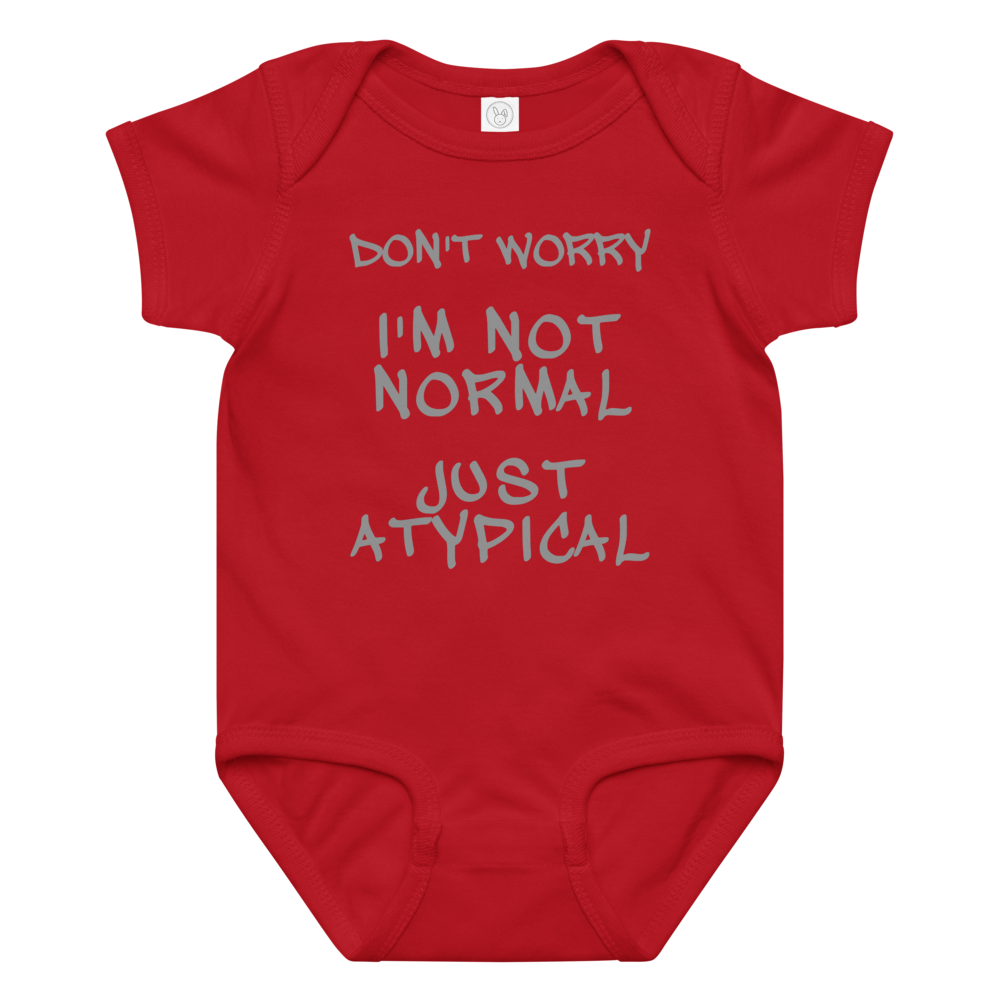 "Don't Worry I'm Not Normal Just Atypical" printed on a red baby jersey bodysuit laying on a flat surface amongst other clothes