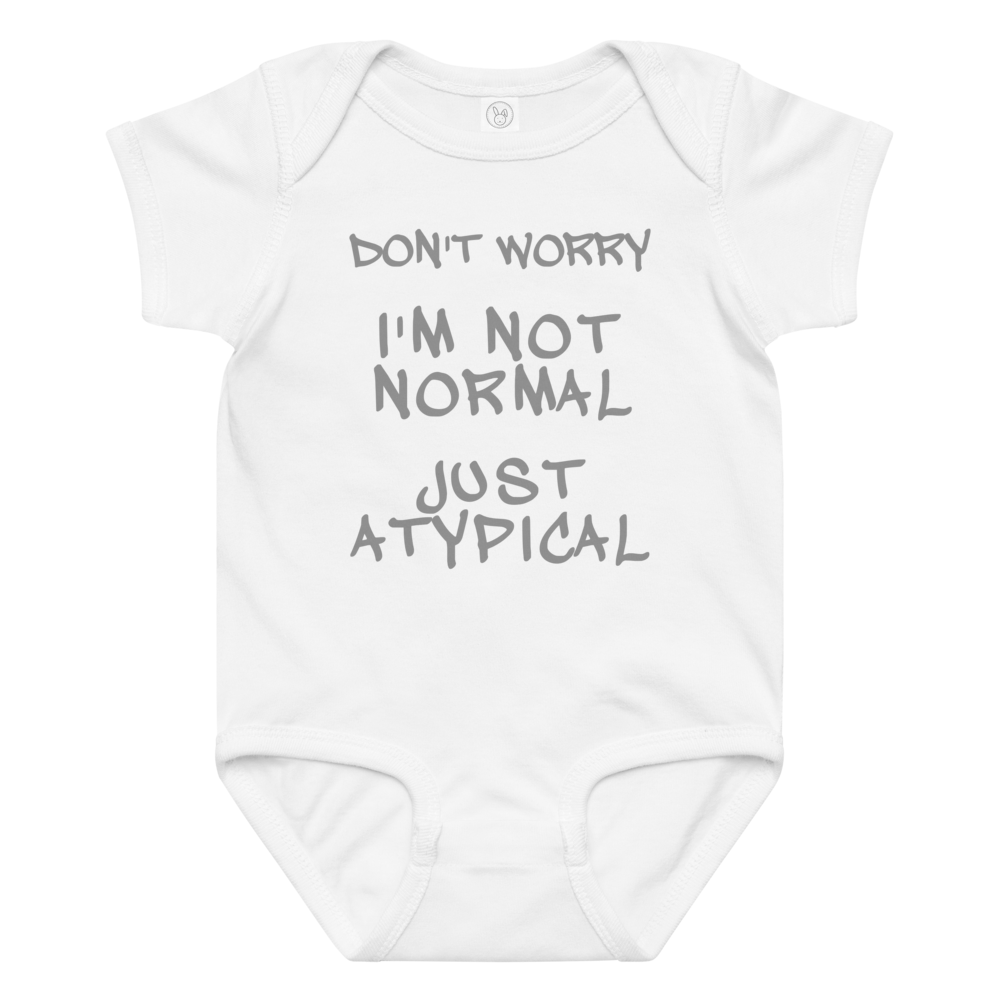 "Don't Worry I'm Not Normal Just Atypical" printed on a white baby jersey bodysuit laying on a flat surface amongst other clothes