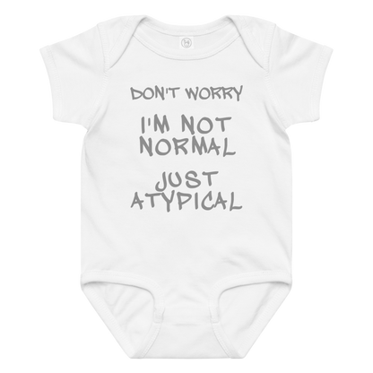 "Don't Worry I'm Not Normal Just Atypical" printed on a white baby jersey bodysuit laying on a flat surface amongst other clothes