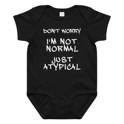 "Don't Worry I'm Not Normal Just Atypical" printed on a black baby jersey bodysuit laying on a flat surface amongst other clothes