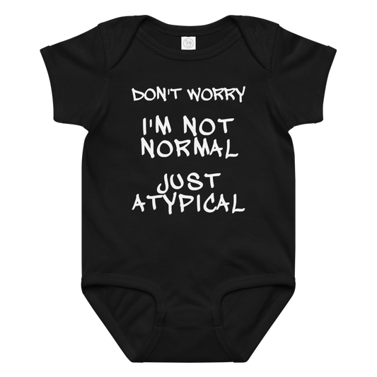"Don't Worry I'm Not Normal Just Atypical" printed on a black baby jersey bodysuit laying on a flat surface amongst other clothes