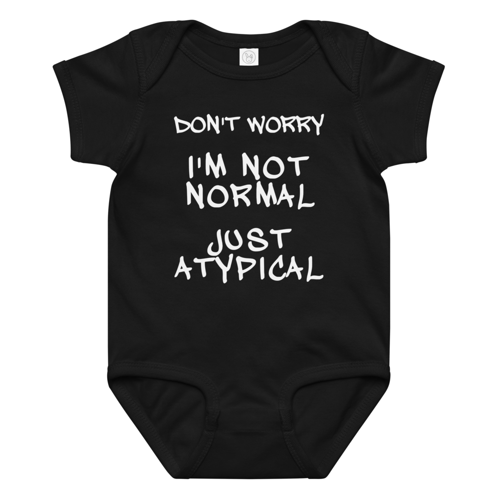 "Don't Worry I'm Not Normal Just Atypical" printed on a black baby jersey bodysuit laying on a flat surface amongst other clothes