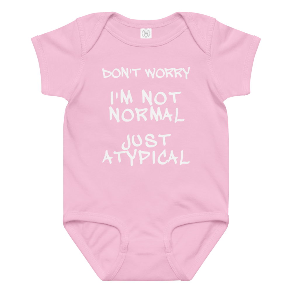 "Don't Worry I'm Not Normal Just Atypical" printed on a pink baby jersey bodysuit laying on a flat surface amongst other clothes