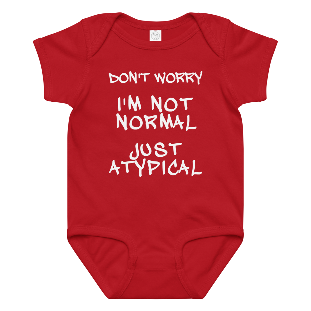 "Don't Worry I'm Not Normal Just Atypical" printed on a red baby jersey bodysuit laying on a flat surface amongst other clothes