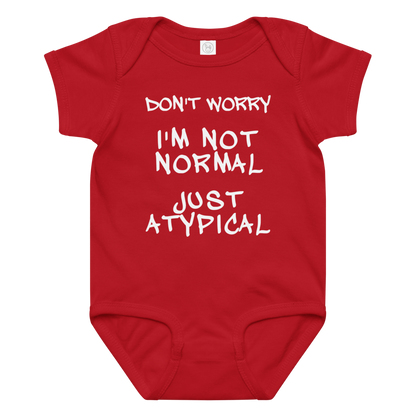 "Don't Worry I'm Not Normal Just Atypical" printed on a red baby jersey bodysuit laying on a flat surface amongst other clothes