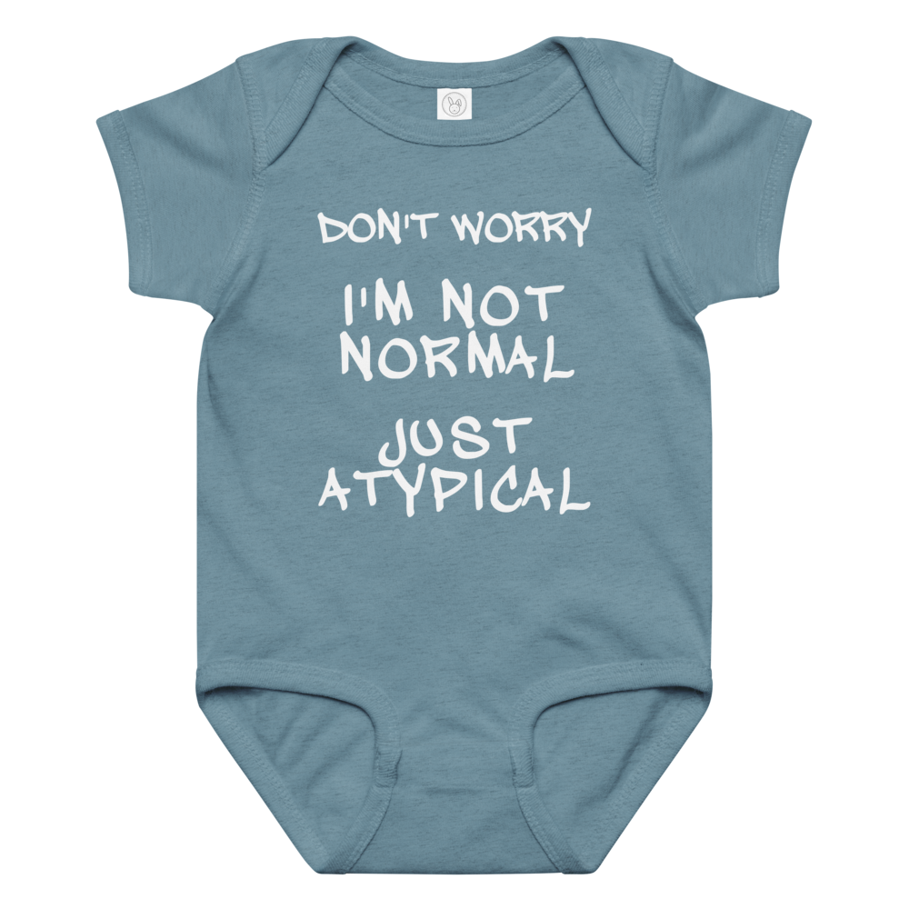 "Don't Worry I'm Not Normal Just Atypical" printed on a vintage indigo baby jersey bodysuit laying on a flat surface amongst other clothes