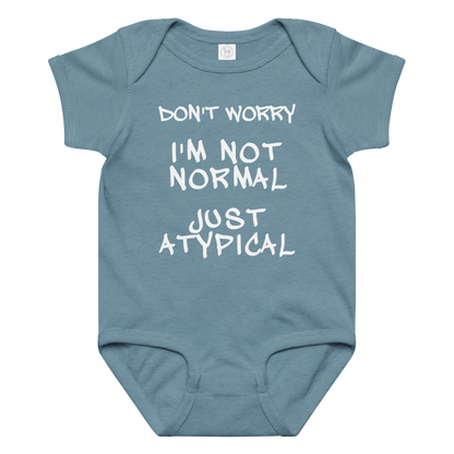 "Don't Worry I'm Not Normal Just Atypical" printed on a vintage indigo baby jersey bodysuit laying on a flat surface amongst other clothes
