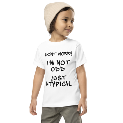 "Don't Worry I'm Not Odd Just Atypical" printed on a white toddler short sleeve tee worn by a male wearing a cap