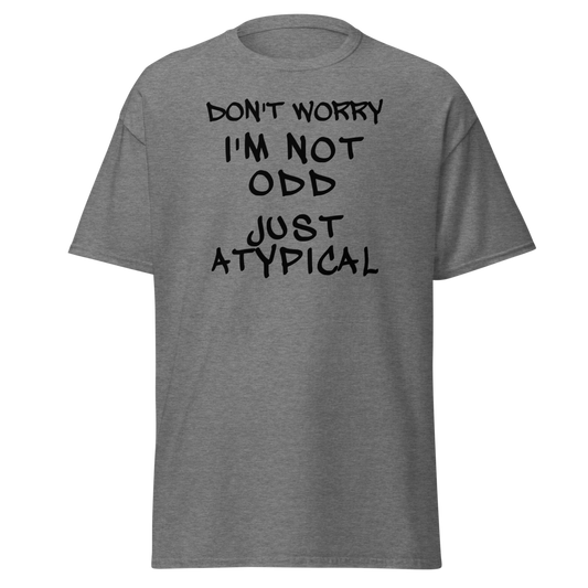 "Don't Worry I'm Not Odd Just Atypical" printed on a graphite heather unisex classic tee laying on a flat surface