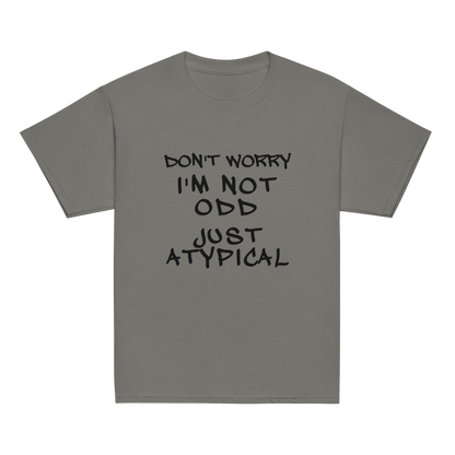 "Don't Worry I'm Not Odd Just Atypical" printed on a charcoal youth classic tee laying on a flat surface