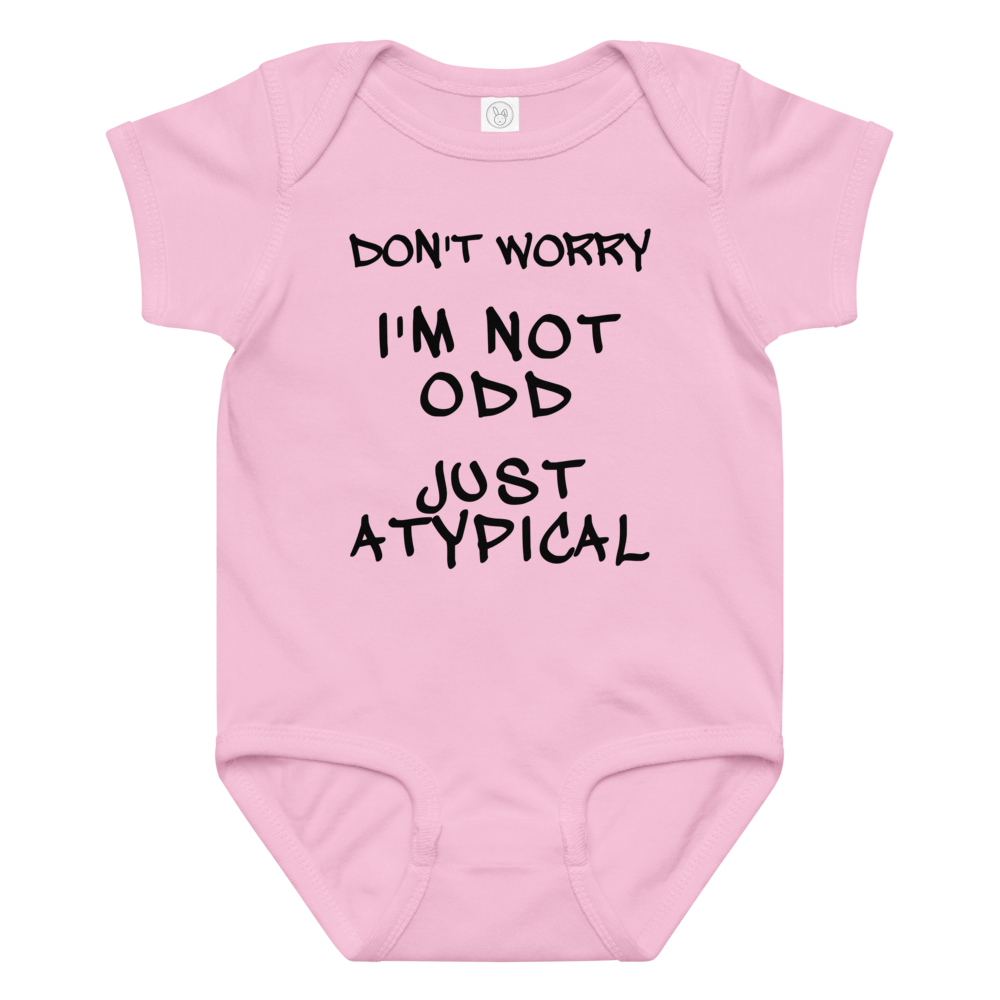 "Don't Worry I'm Not Odd Just Atypical" printed on a pink baby jersey bodysuit laying on a flat surface amongst other clothes